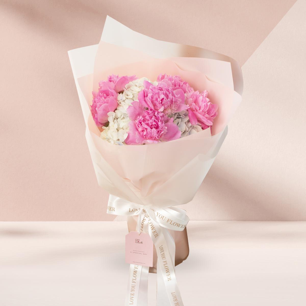 A339 Bouquet of 6 pink peonies, 2 light blue hydrangeas wrapped in Cotton Candy paper with gold and white ribbons.