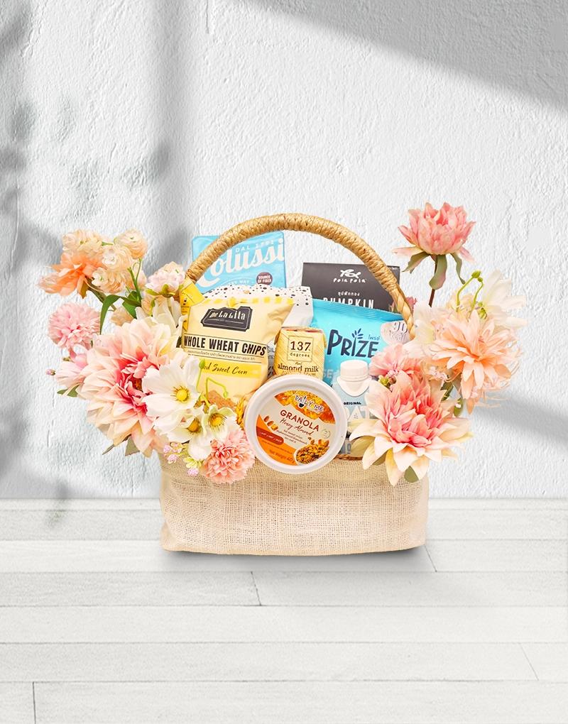 Gift Basket with a selection of organic health products, adorned with artificial flowers in light pink and old rose