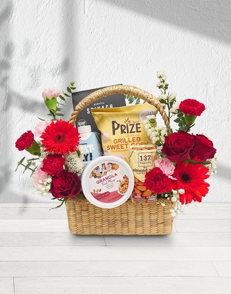 Gift Basket with organic health products, adorned with fresh red flowers like red roses and red gerberas.