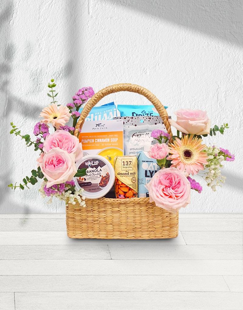 Healthy Hampers with a variety of organic gifts, adorned with sweet-toned pink flowers like roses, gerberas, and carnations.