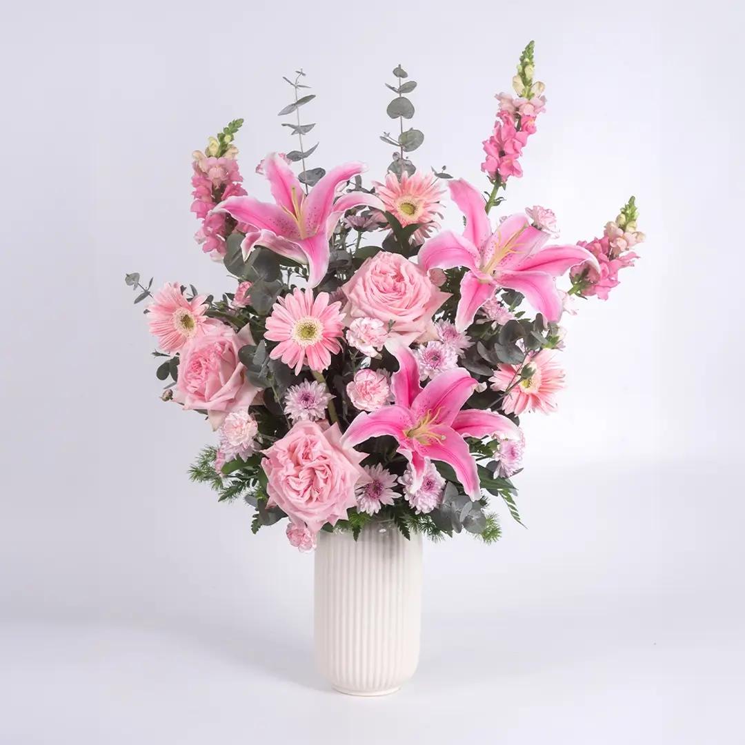 แจกันดอกไม้โทนสีชมพู  โดดเด่นด้วยดอกลิลลี่ ดอกกุหลาบ และสต๊อค เพิ่มความละมุนด้วยดอกคาร์เนชั่นสเปรย์จัดในแจกันสีขาว ส่งฟรี