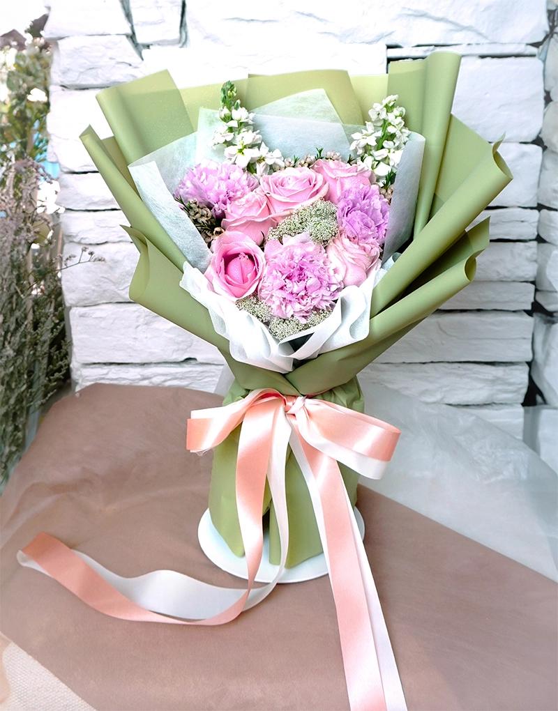 A387 Heart Blooming bouquet with white stock, light pink peonies, and roses, wrapped in olive paper.
