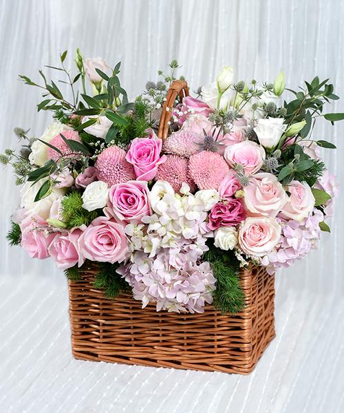 กระเช้าดอกไม้สด ตกแต่งด้วยดอกไม้โทนสีชมพูหลายชนิด ในกระเช้าทรงสี่เหลี่ยม