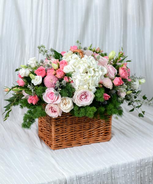 กระเช้าดอกไม้โทนสีชมพู ประดับด้วยดอกไม้กว่า 7 ชนิด บนตะกร้าไม้ทรงสี่เหลี่ยม