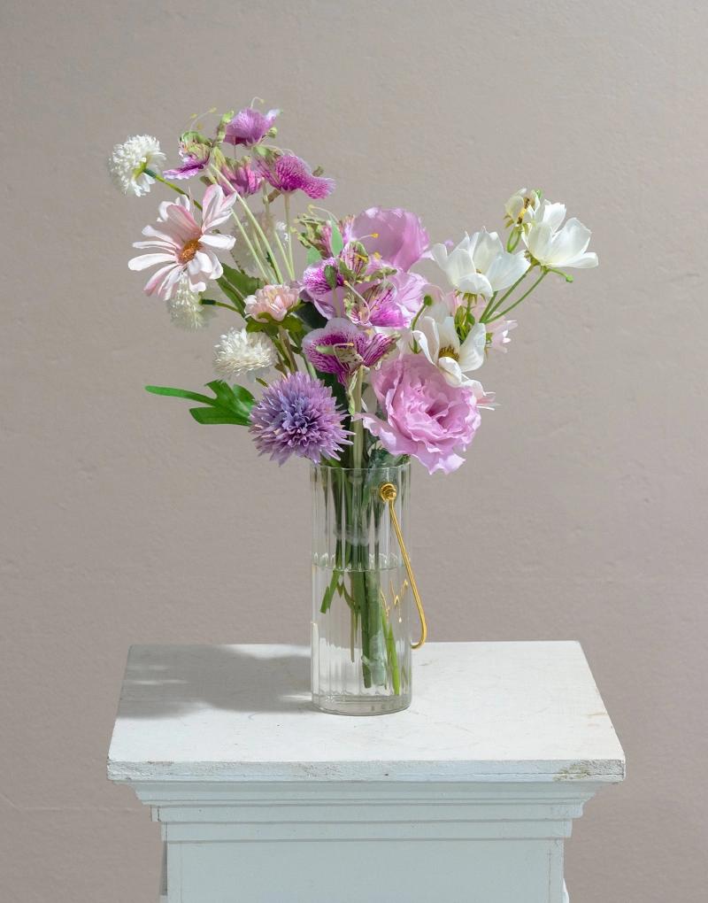 แจกันดอกไม้ประดิษฐ์ CF014 จัดด้วยดอกไม้โทนสีม่วงอ่อน ทั้งดอกมัม และดอกพุดตาล และอื่น ๆ บรรจุลงในแจกันแก้วหูหิ้วสีทอง สุดมินิมอล