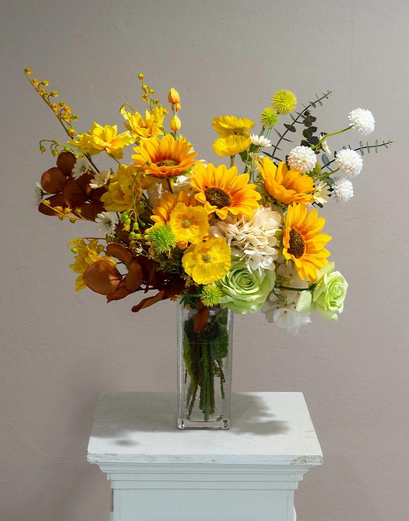 แจกันดอกไม้ประดิษฐ์ CF015 ตกแต่งด้วยดอกทานตะวันจัดมาในโทนสีเหลืองสดใสลงบนแจกันแก้วทรงสูง