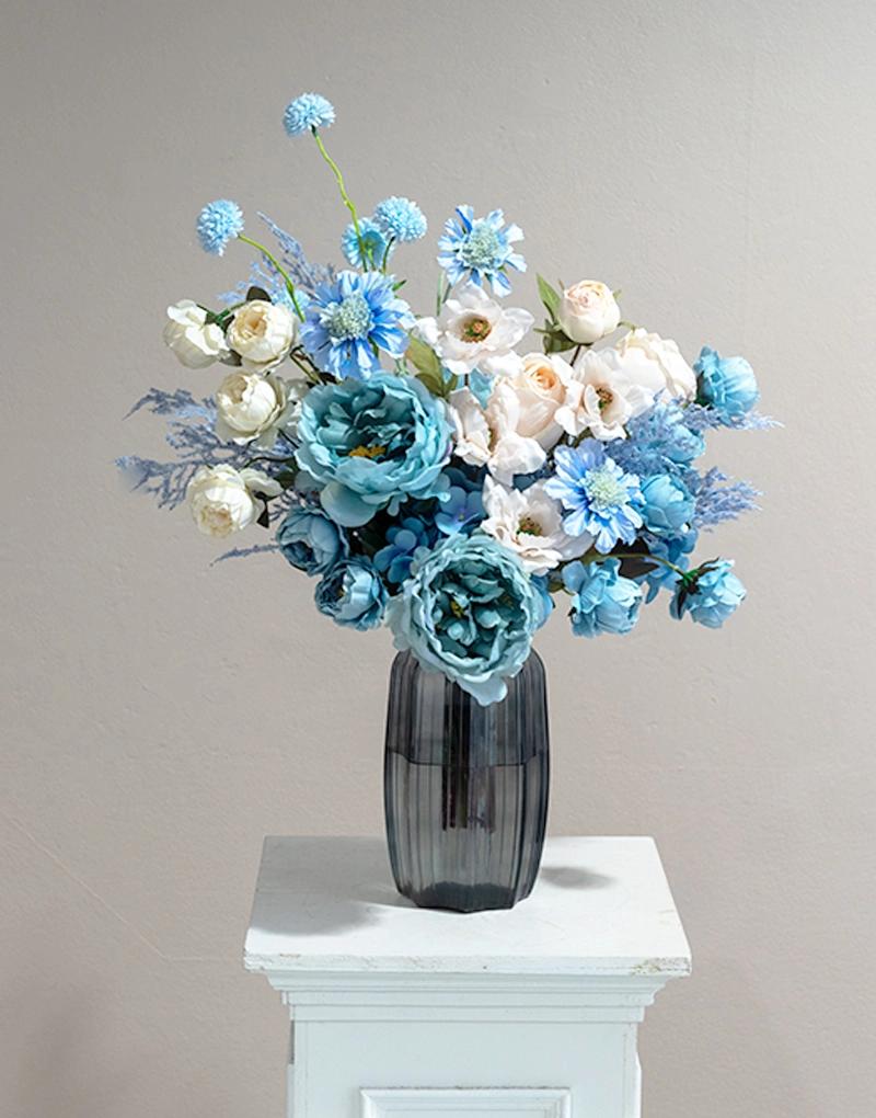แจกันดอกไม้ประดิษฐ์ CF007 จัดด้วยดอกไม้โทนสีฟ้าและครีม บรรจุในแจกันแก้วสีเทาทรงหกเหลี่ยม  