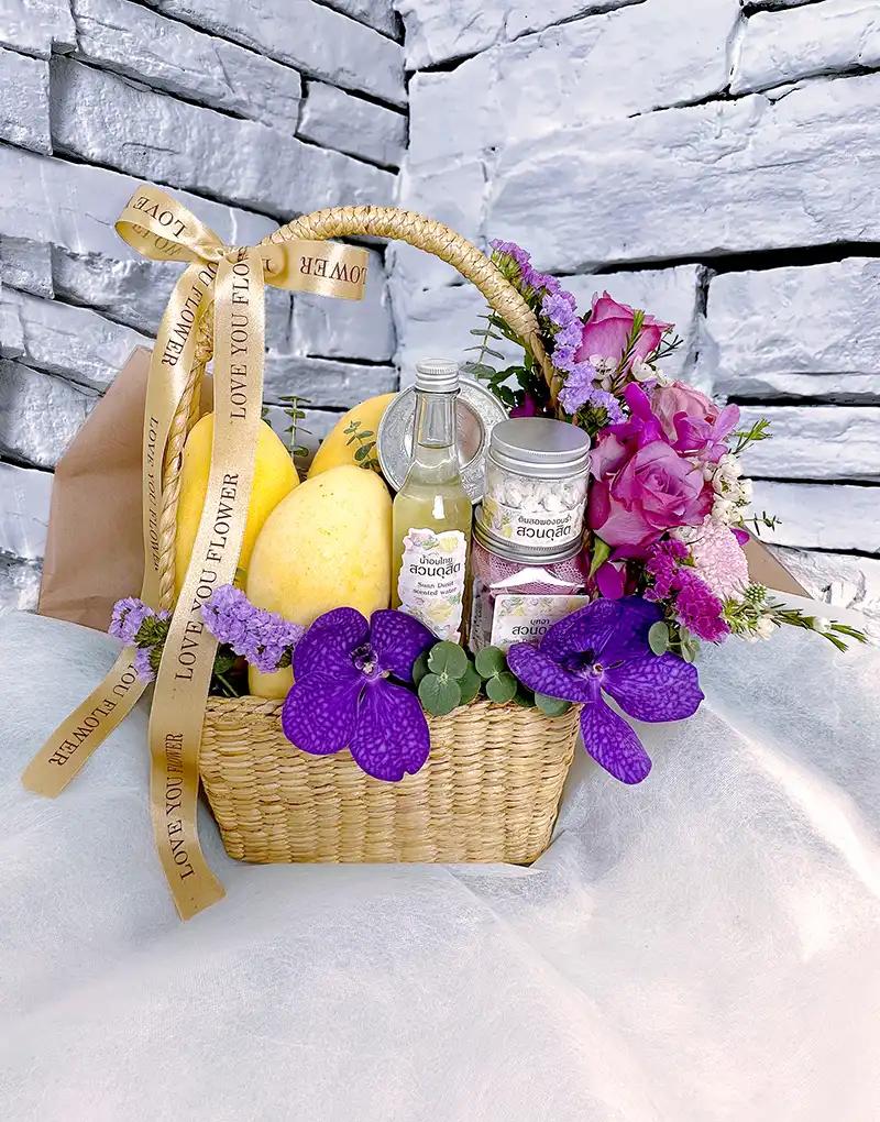 "Songkran gift basket BFS005 with ripe mangoes and Thai scented water set, adorned with purple flowers.