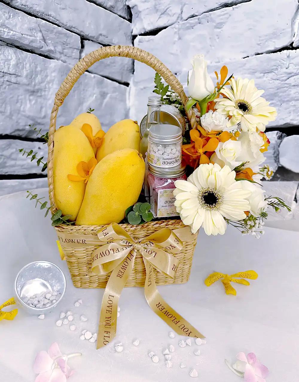 "Songkran gift basket BFS006 with ripe mangoes and Thai scented water set, adorned with cream-white flowers.