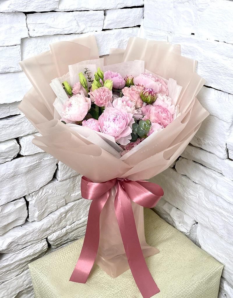 A389 bouquet of 10 soft pink peonies, enhanced with lisianthus and wrapped in Cherry Blossom-colored paper.