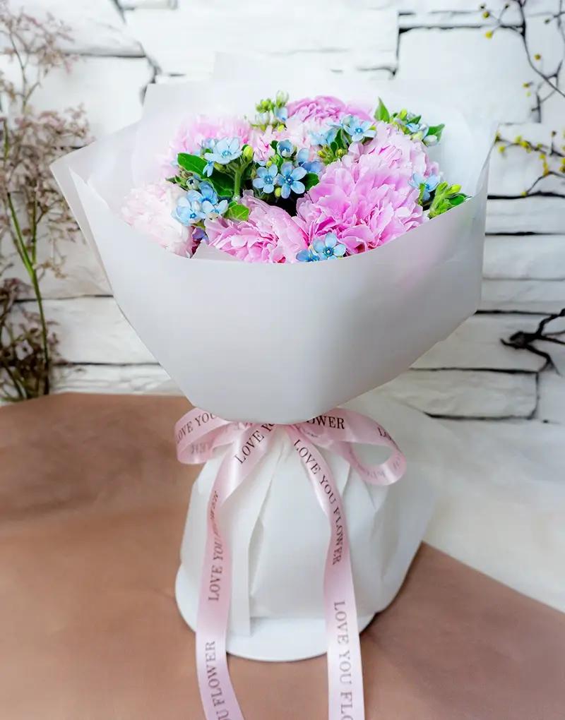 ช่อดอกไม้สดโทนสีชมพู ฟ้า และขาว ห่อกระดาษสีขาวผูกริบบิ้นสีชมพู