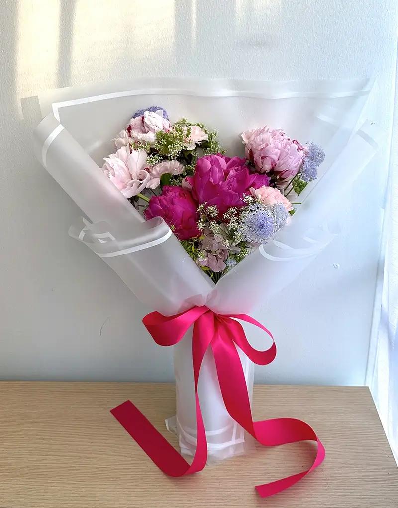 ช่อดอกไม้สดโทนสีชมพูและขาว ห่อกระดาษสีขาวผูกริบบิ้นสีชมพูอ่อน