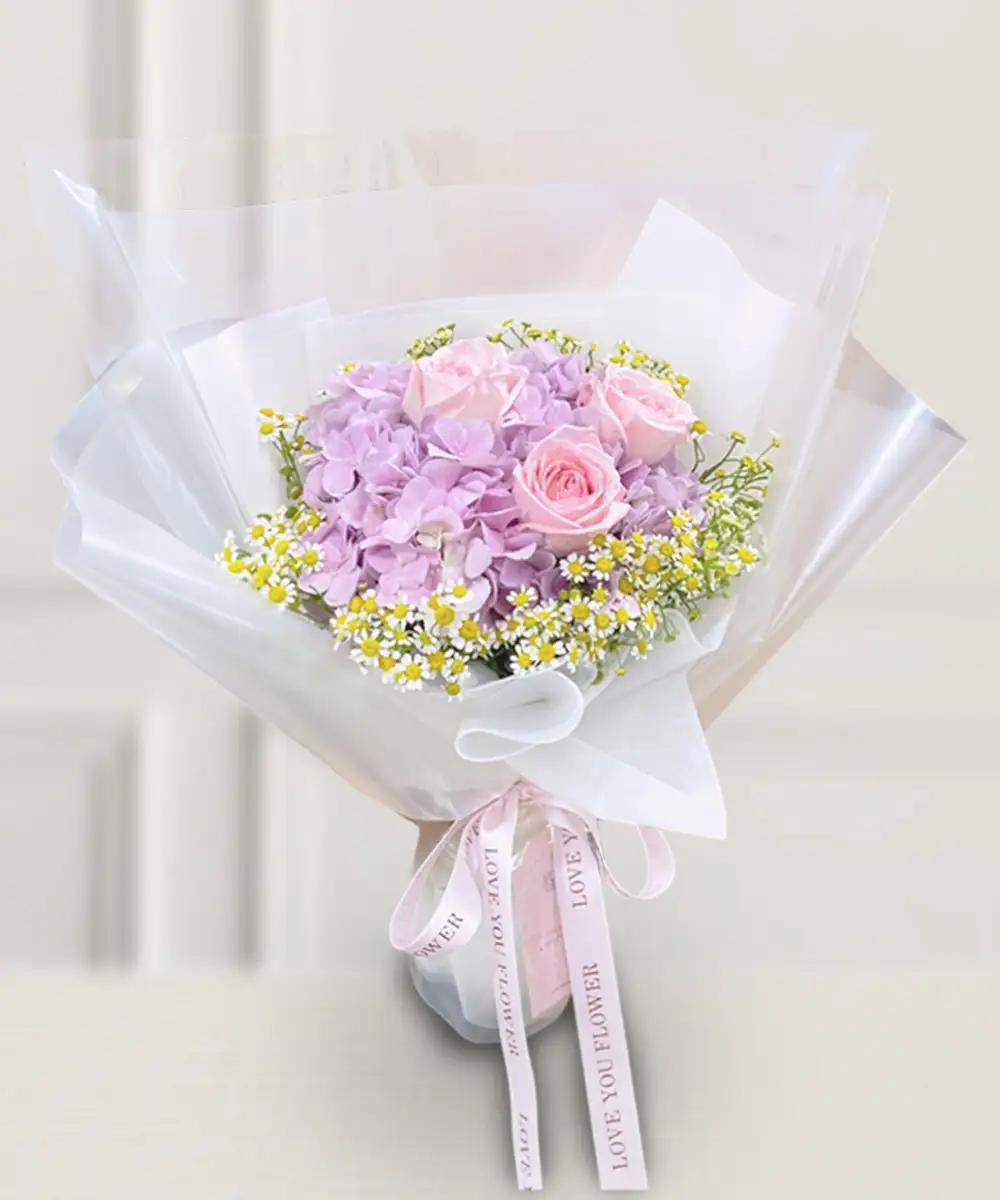 ช่อดอกไม้สดโทนสีชมพูและม่วง ห่อกระดาษสีขาวใสผูกริบบิ้นสีชมพู