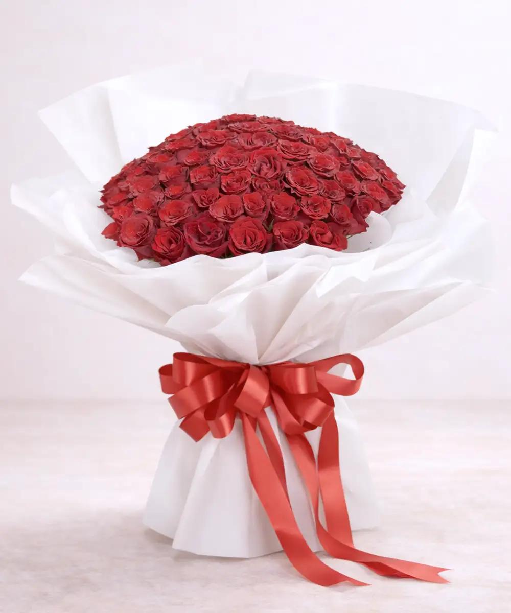 ช่อดอกกุหลาบสีแดงจำนวนมาก ห่อกระดาษสีขาวผูกริบบิ้นสีแดง